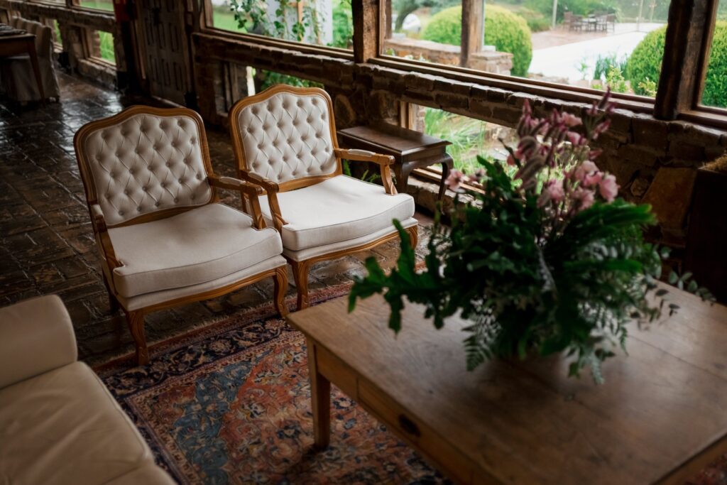 Elegant antique chairs in a rustic indoor wedding venue featuring floral arrangements and vintage decor.