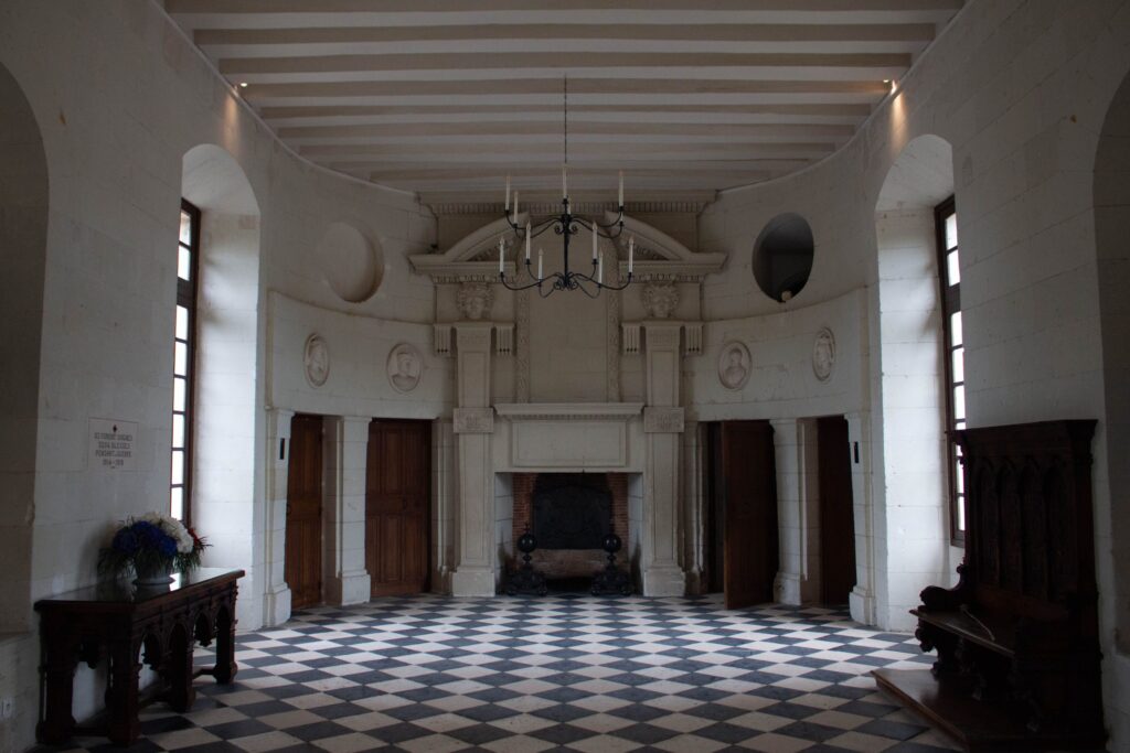 An elegant hall inside Chenonceau Castle featuring a checkered floor and classic decor.